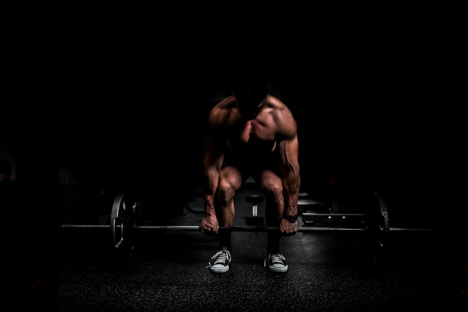 shirtless man lifting barbell in gym