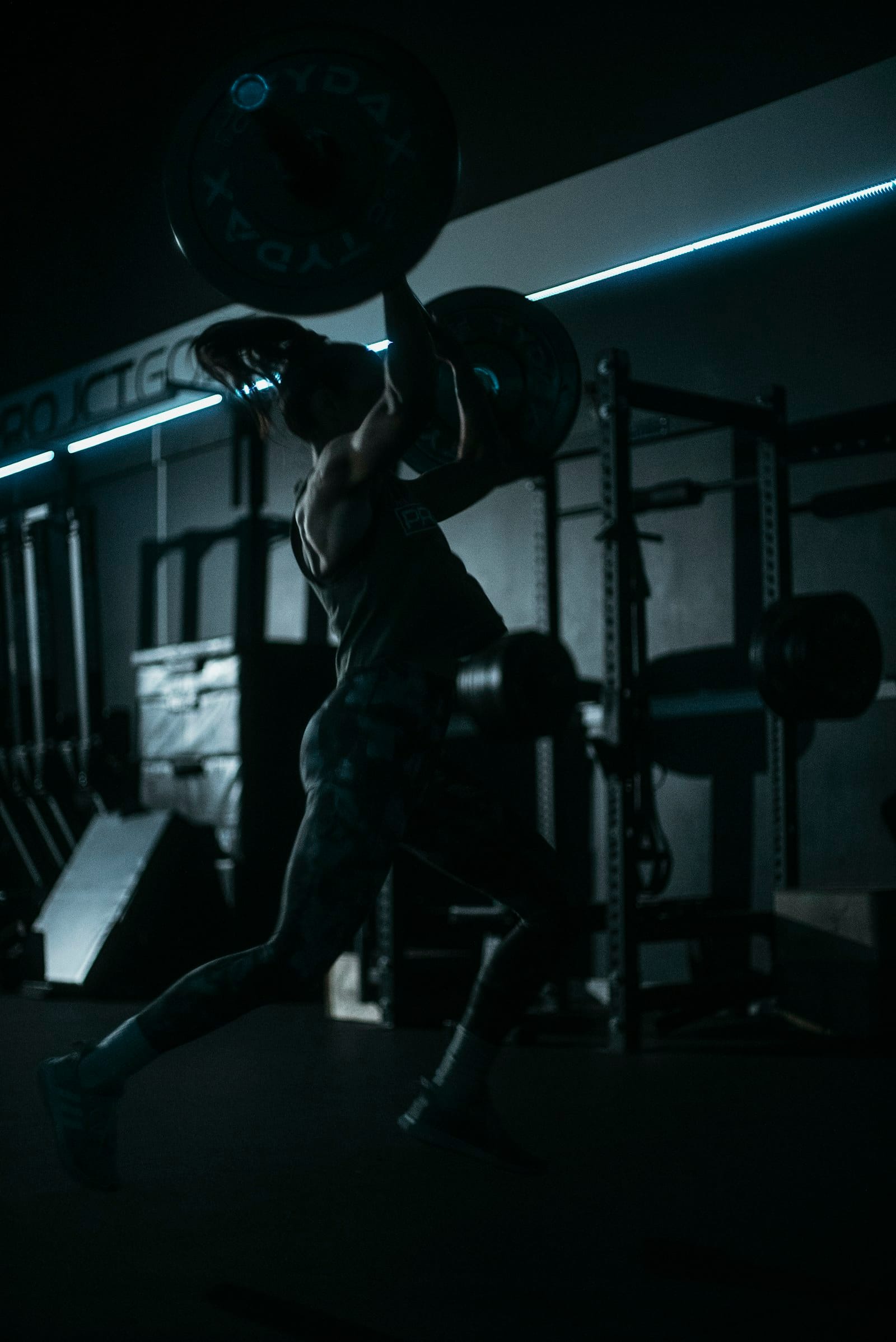 a man lifting a barbell in a dark gym