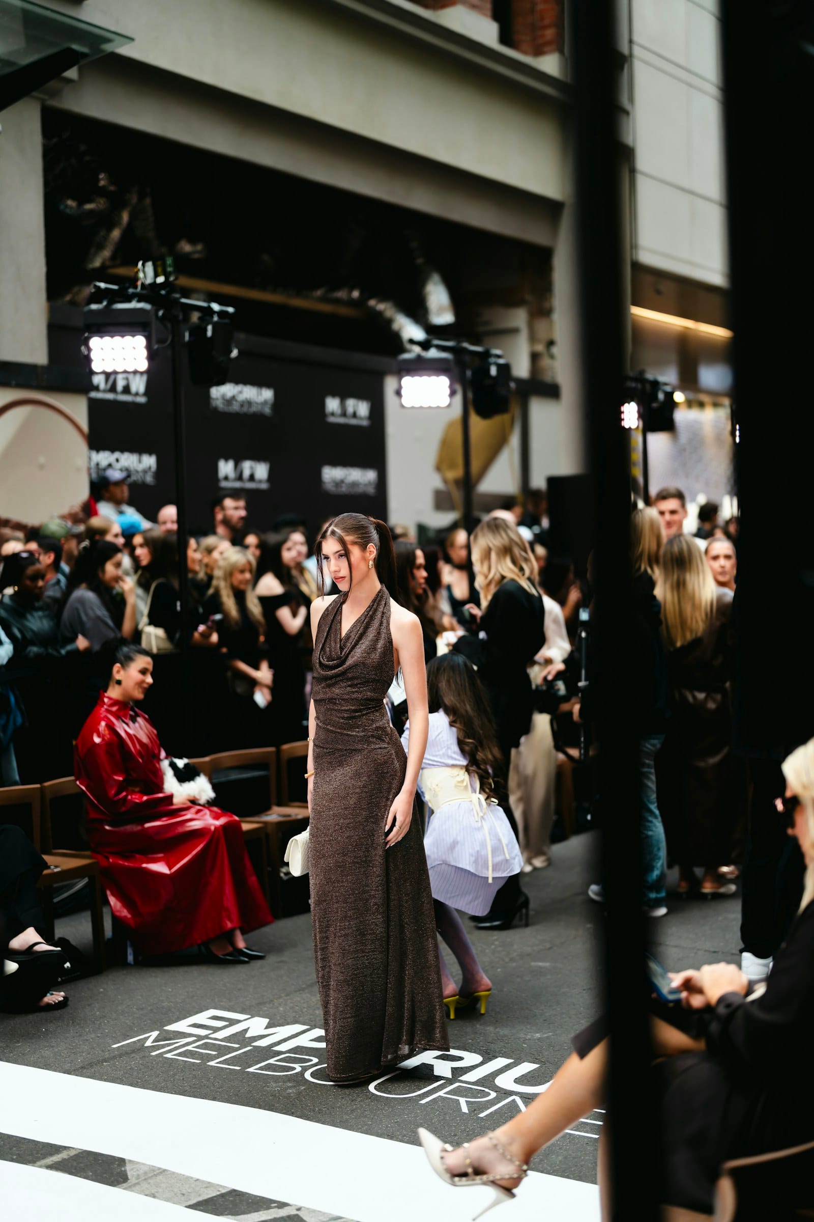 Model walks runway at fashion event with audience